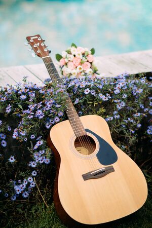Guitar is on a background of blue flowers and a wedding bouquet of the bride.の写真素材