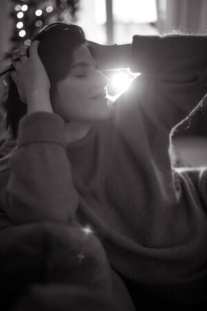 Woman sits on sofa and rests. Backlight. Black and white image.の写真素材