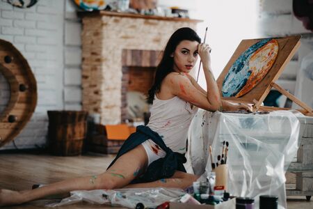 The artist stained with paint draws a picture in an art workshop in a creative mess.の写真素材