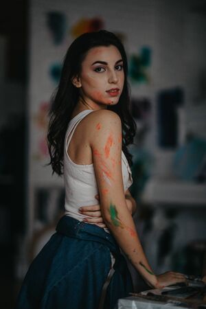 The artist stained with paint stands in an art workshop.の写真素材