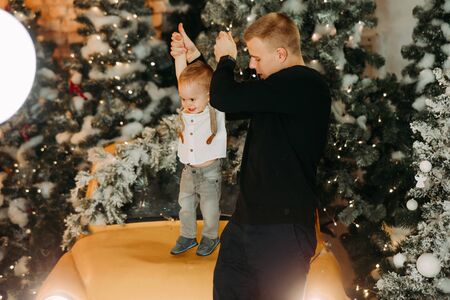 Father plays with his little son against background of Christmas tree nd decorations.の写真素材