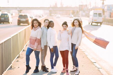 Multiracial group of friends from five young women walks on city street. The concept of friendship and unity between different human races.の写真素材