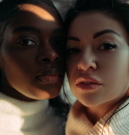 The portrait of young african and asian women with sunlit areas. The concept of friendship and unity...