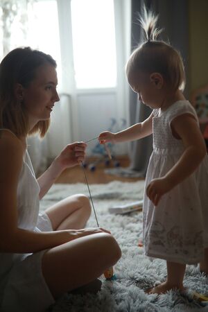 Mother plays with her little daughter at the room on the carpet.の写真素材