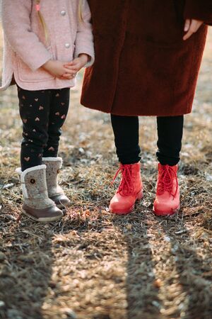 Child and woman feet are in boots on the background of pine needles in the forest.の写真素材