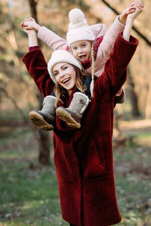 Mother and daughter play, have fun and laugh cheerful while walking in the forest.