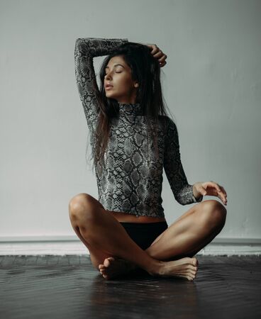 Young woman posing in the studio sitting on the floor.の写真素材
