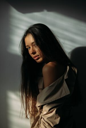 Portrait of a young woman in a coat with a bare shoulder at studio.の写真素材