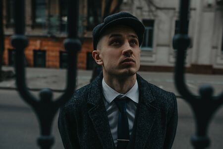 A man posing in the image of an English retro gangster of the 1920s dressed in Peaky blinders style...