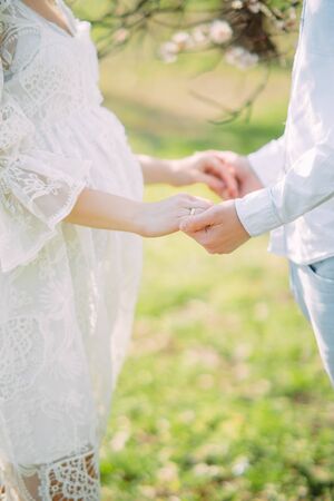 Pregnant woman and man stand and hold each other hands while walk in the park.の写真素材