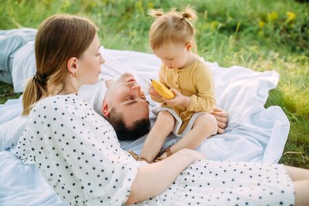Family with little daughter rests during picnic in the park.の写真素材