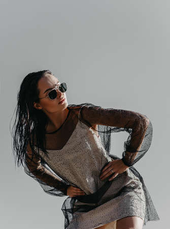 Pretty woman in sunglasses poses against background of gray sky.の写真素材