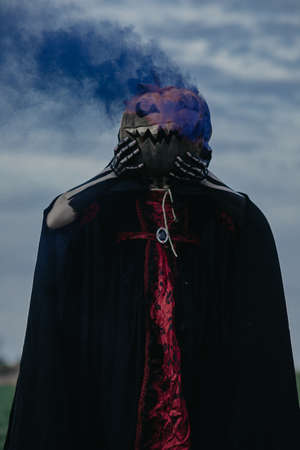 Young woman stands in Halloween costume of death with painted skeleton on her body and holds...