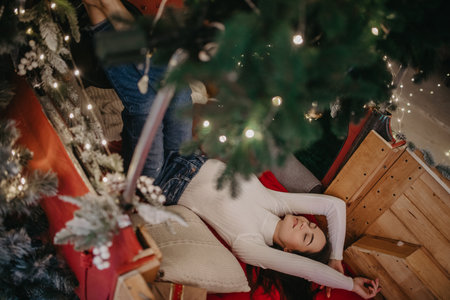 Happy woman lies on the floor against background of Christmas tree and decorations. Top view.の写真素材