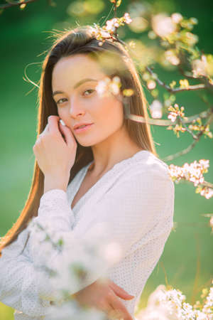 Portrait of young brunette woman among the spring blossoming cherry trees.の写真素材