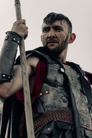 Portrait of ancient Spartan warrior in armor with spear in his hand against sky background.の写真素材