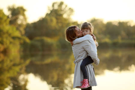 Mother walks together with her daughter in park near river.の写真素材