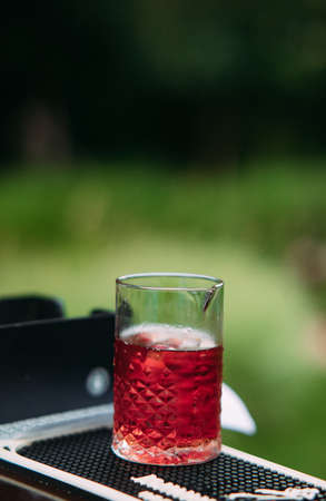 Transparent jug with red drink stands on the table against background of green grass. Closeup.の写真素材