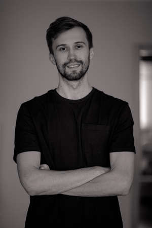 Black and white portrait of young smiling man with beard.