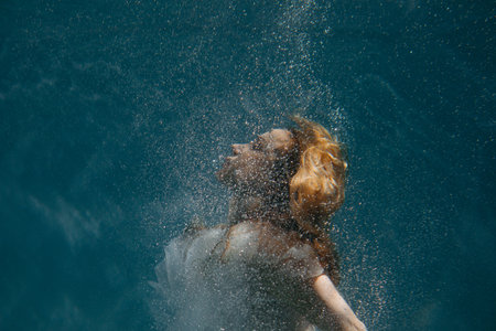 Portrait of beautiful swimming and diving woman in bridal dress underwater.の写真素材