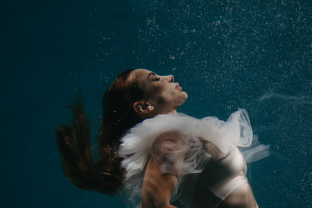 Portrait of beautiful swimming and diving woman in bridal dress underwater.の写真素材