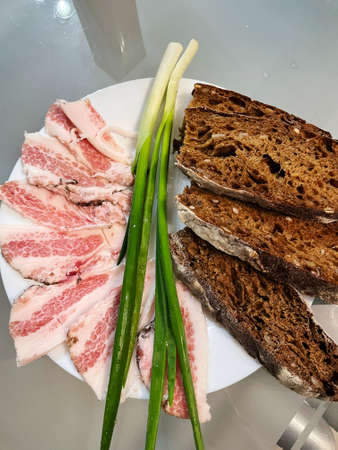 Top view of a plate with cut slices of rye bread, pork lard and green onion feathers. closeup.の写真素材