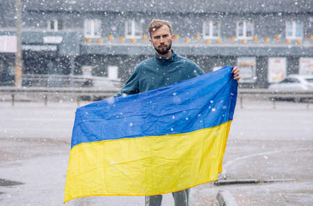 Young angry man holds ukrainian flag in his hands and protests against Russia attack and invasion in Ukraine. Russian concept aggression.の写真素材