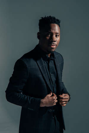 Young african man in jacket stands against gray background.の写真素材