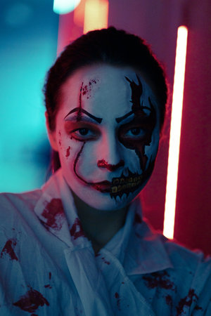 Young woman portraying bloodthirsty zombie with horror wounds on her face and bloody clothes. Scary image for Halloween.の写真素材