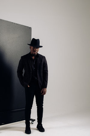 Young african man in suit and hat poses in studio.