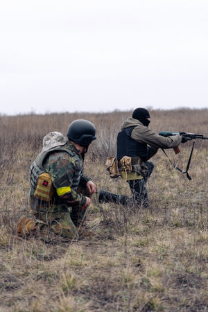 Group of armed Ukrainian soldiers aims in enemy in steppe against background of dry grass and sky. War in Ukraine. Russian aggression and military invasion in Ukraine.の写真素材
