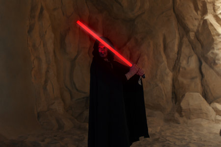 Kyiv, Ukraine - April 14, 2023: Cosplayer portraying character Kylo Ren from the Star Wars universe with red blade lightsaber in his hand among sandy canyon.のeditorial素材