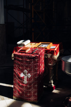 Holy Bible and cross are on the lectern near baptismal font with blessing water against background of icons for newborns baptism rite in Orthodox Ukrainian church.の写真素材