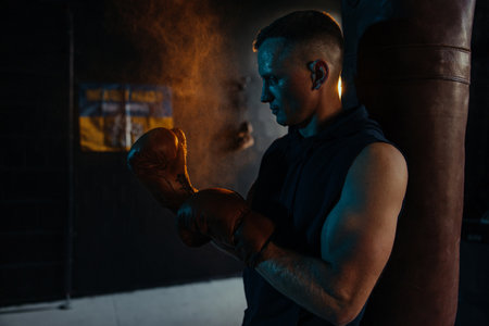 Portrait of male boxer with drops of perspiration on his face after exercising in gym against background of Ukrainian flag. backlight.の写真素材