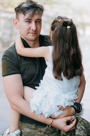 Portrait of happy Ukrainian soldier returning from the war, meeting his little daughter and embracing her. War in Ukraine. Russian military invasion in Ukraine. War and children. close-up.の写真素材