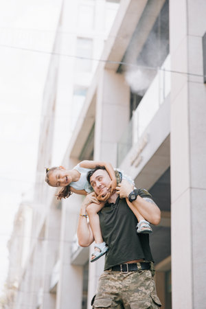 Little Ukrainian girl meets her father from the war during his vacation and cheerful plays with him. War in Ukraine. Russian military invasion in Ukraine. War and children.の写真素材