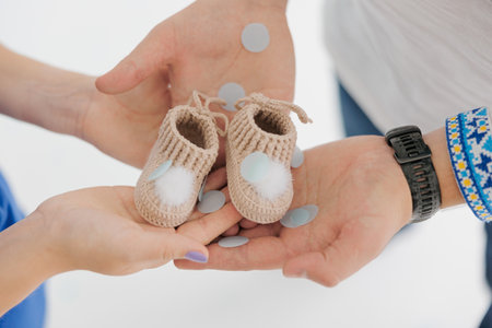 Future parents holding in their hands boots for newborn baby. Family waiting for a baby to be born. Ukrainian embroidered shirt. Closeup.の写真素材