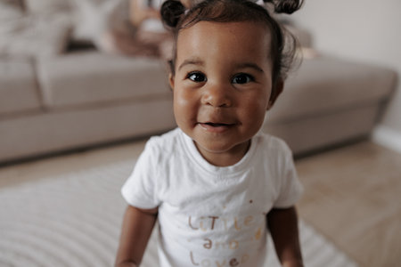 Portrait of joyful mixed race toddler girl in room. Afro-Caucasian little girl. Concept of...