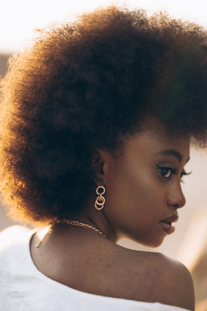 Portrait of young African woman posing outdoor at sunset. Image with backlit.