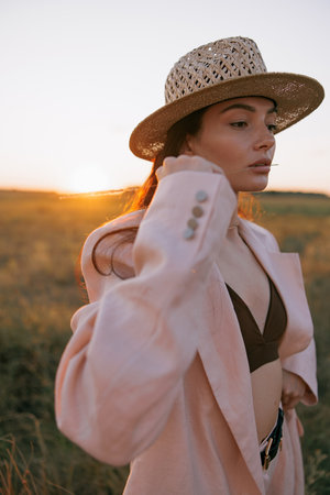 Portrait of young pretty woman in straw hat on meadow at sunset. Backlight.の写真素材