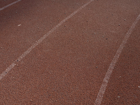 Close-up of rubberized running track on stadium with marked lanes and textured surface. Athletics, grip, non-slip surface. Textures and backgrounds for sport, fitness and training concepts.の写真素材