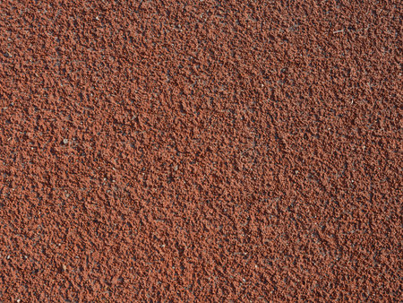 Close-up and top view to rubberized brown running track on stadium with textured surface. Athletics, grip, non-slip surface. Textures and backgrounds for sport, fitness and training concepts.の写真素材