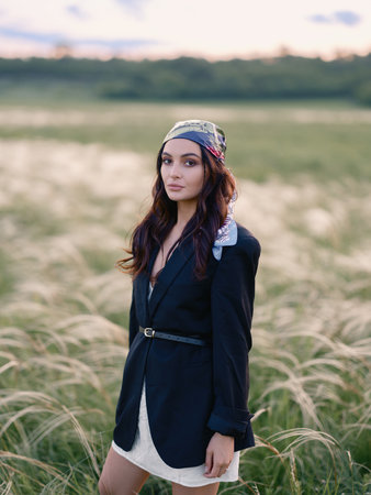 Young woman walking among feathergrass in steppe at sunset against beautiful landscape. Summer outdoor scene with feather grass in steppe in Ukraine. Backlit. Close-up.の写真素材