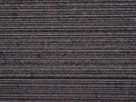 Close-up surface of striped and ribbed red and black facing granite tiles. Decorative facade tile with natural stone texture. Background for architecture, construction, design, and material texture.の写真素材