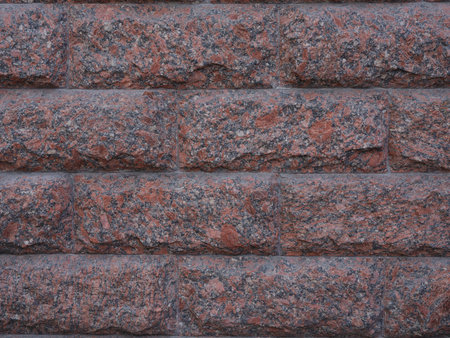 Close-up surface of red and black facing granite tiles in form of rectangular bricks. Decorative facade tile with natural stone texture. Background for architecture, construction, design.の写真素材