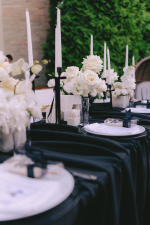 Sophisticated black-and-white outdoor festive reception with floral centerpieces and tall candles...