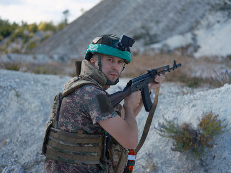 Ukrainian soldier in a tactical gear, holding a rifle in combat readiness in a chalk quarry. Fight...