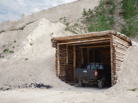 Rear view of a military pickup truck parked inside a wooden dugout or shelter in a quarry. The vehicle is camouflaged, ready for a mission.の写真素材