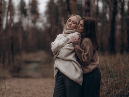 Emotional portrait young lesbian couple hugging from side with closed eyes in nature. Showing deep comfort, support, serenity, and love in diverse LGBT relationships.の写真素材