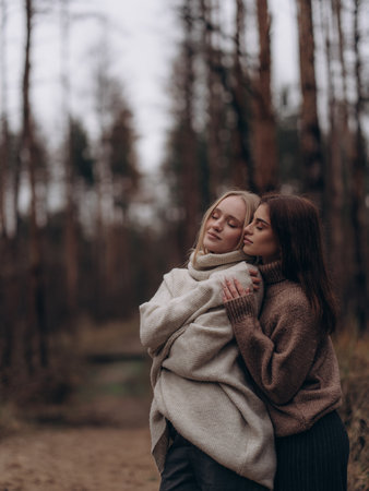 Emotional portrait young lesbian couple hugging from side with closed eyes in nature. Showing deep comfort, support, serenity, and love in diverse LGBT relationships.の写真素材